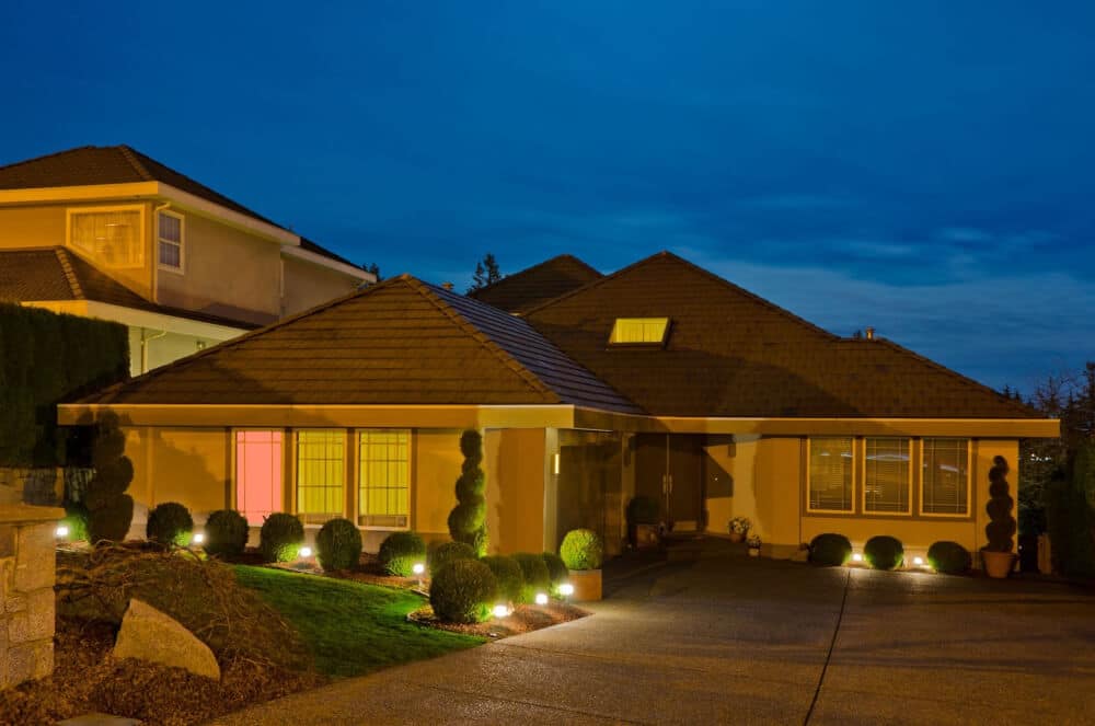 A home at dusk equipped with lit outdoor landscape lighting stakes